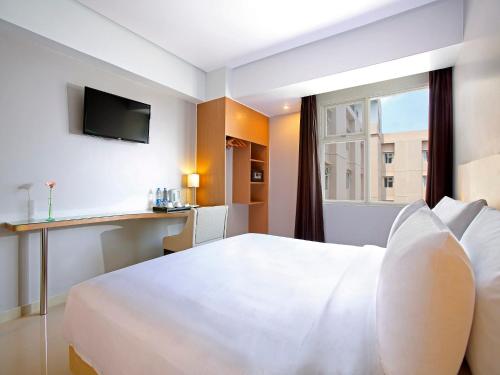 um quarto de hotel com uma cama branca e uma janela em Hotel Santika Depok em Depok