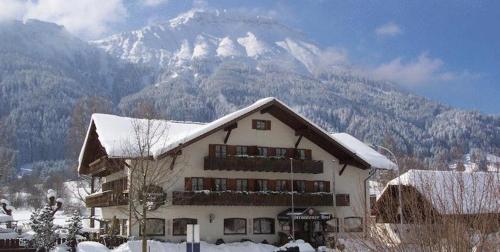 a building with a snow covered mountain in the background at Hotel Pfrontener Hof in Pfronten
