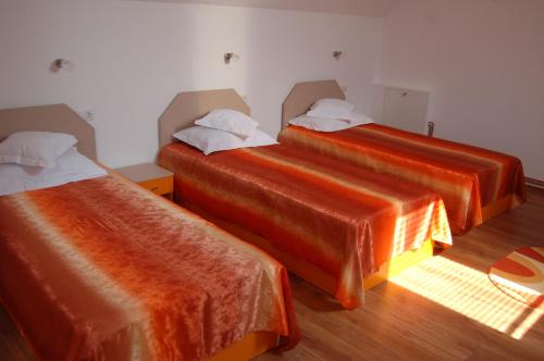 2 camas con sábanas de color naranja en una habitación en Pensiunea Bogdan, en Novaci-Străini