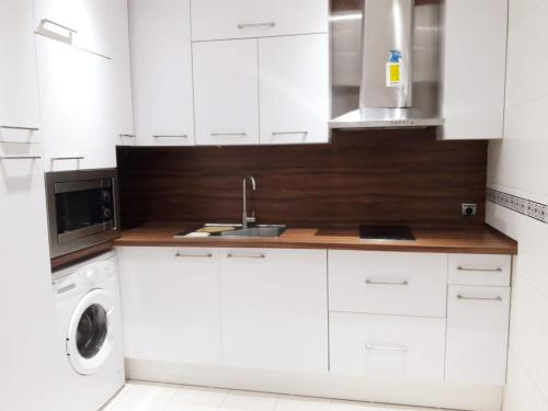 cocina blanca con fregadero y lavadora en Bel appartement au centre ville et de la plage en Ceuta