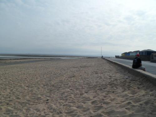 a person sitting on a wall on the beach at Wavecrest Lodge in Fleetwood