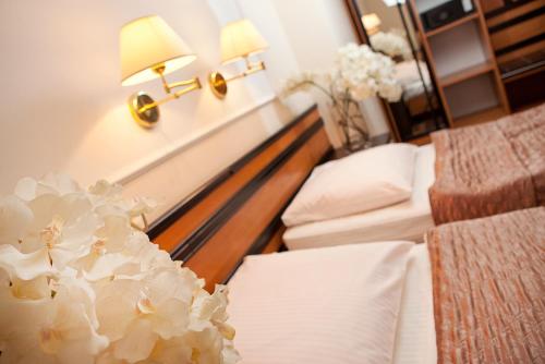 a hotel room with two beds and flowers at Wzgórze Toskanii Conferences & Restaurant in Przeźmierowo