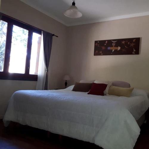 - une chambre avec un lit blanc et une fenêtre dans l'établissement Bosque Peralta Ramos. Zorzales del Bosque, à Mar del Plata
