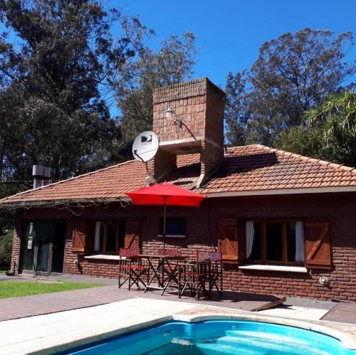 une maison en briques avec une table et un parapluie rouge dans l'établissement Bosque Peralta Ramos. Zorzales del Bosque, à Mar del Plata