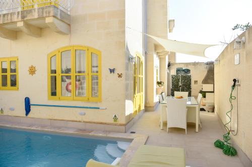 a house with a swimming pool next to a building at Melita in Xagħra
