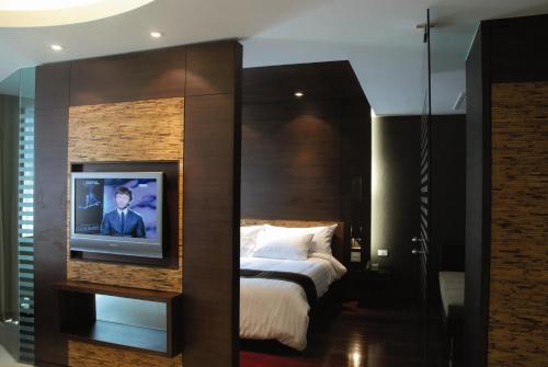 a bedroom with a bed with a tv on a wall at Tara Mantra Cha-Am Resort in Cha Am
