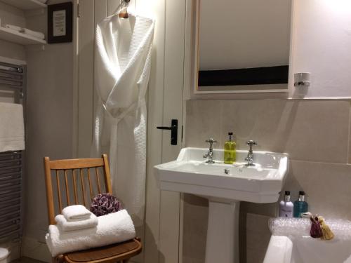 a white bathroom with a sink and a chair at Low Raisgill B&B in Buckden