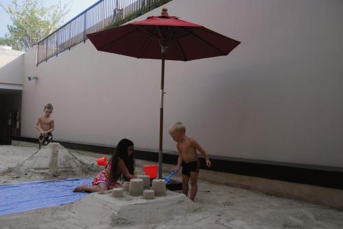 a boy and a girl playing in the sand with an umbrella at Tara Mantra Cha-Am Resort in Cha Am