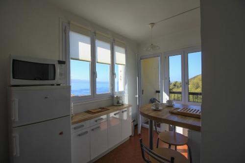 une cuisine avec des armoires blanches et une table avec un micro-ondes dans l'établissement Appartement vue mer, à Ajaccio