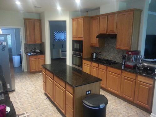 a kitchen with wooden cabinets and a black counter top at Large Modern Residence with private guest, family room & business office in Missouri City