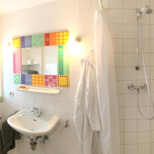 a white bathroom with a sink and a mirror at Stadthaus Rothensande in Schleswig