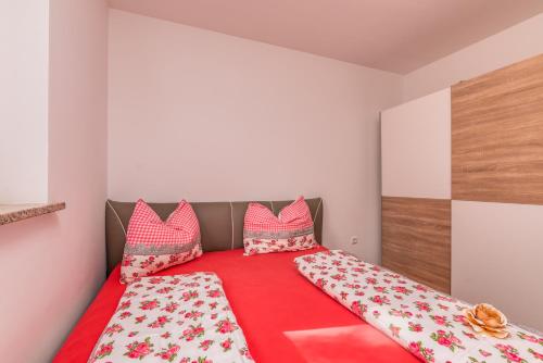 a bedroom with a bed with red sheets and pillows at Apartment M&M Klimno in Klimno