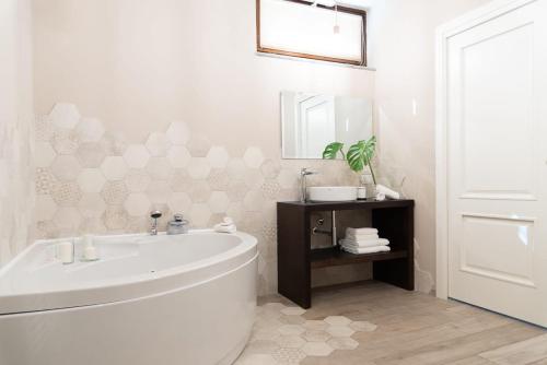 Baño blanco con bañera y lavamanos en B&B Villa Fulvia en Alba