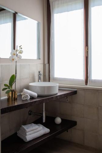 a bathroom with a sink and two windows and towels at B&B Villa Fulvia in Alba