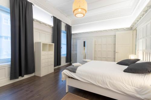 Schlafzimmer mit einem großen weißen Bett und schwarzen Vorhängen in der Unterkunft CENTRAL by Kyosai in Bilbao