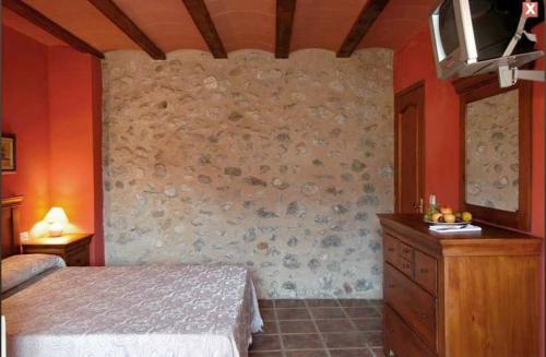 a bedroom with a bed and a stone wall at Hotel Rural Barranc De L'ínfern in Vall de Ebo