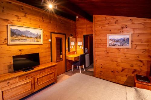 a bedroom with a television and a desk in a cabin at Skotel Alpine Resort in Whakapapa Village