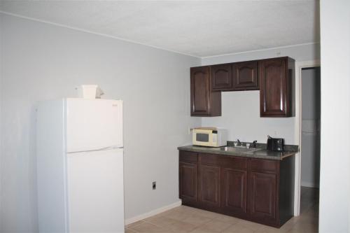 a kitchen with wooden cabinets and a white refrigerator at Winnisquam Lake Inn in Tilton