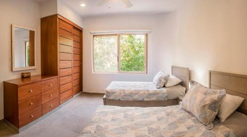 1 dormitorio con 2 camas, vestidor y ventana en Gulliver condo - Free beach club access & Bikes en Tulum