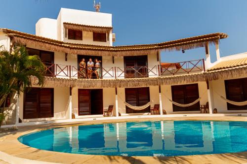 people standing on the balcony of a house with a swimming pool at Pousada Porto Azul in Cumbuco