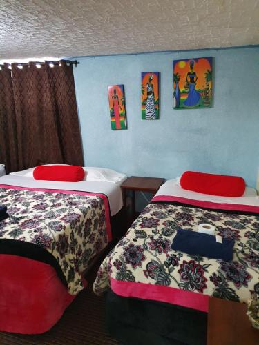 a room with two beds and paintings on the wall at hotel kasa kamelot 2 in Quetzaltenango