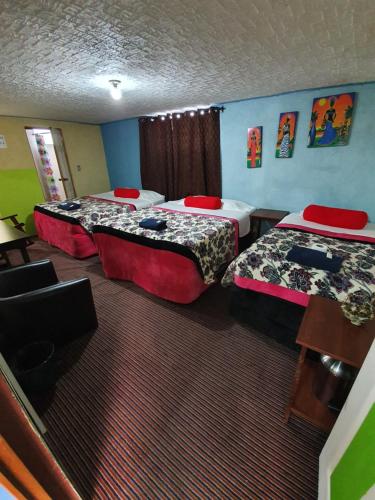 a room with two beds and a table and chairs at hotel kasa kamelot 2 in Quetzaltenango