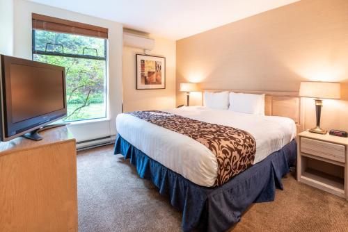 a hotel room with a bed and a flat screen tv at The Ironwood on Blueberry Hill in Whistler