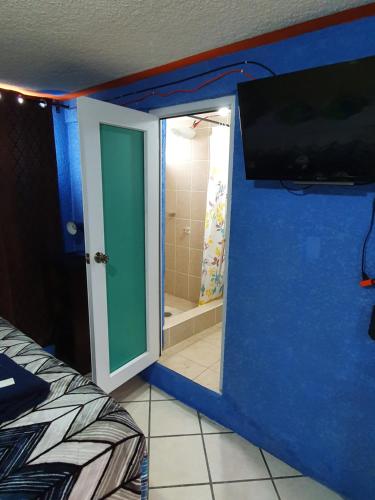 a room with a bathroom with a shower and a television at hotel kasa kamelot 2 in Quetzaltenango