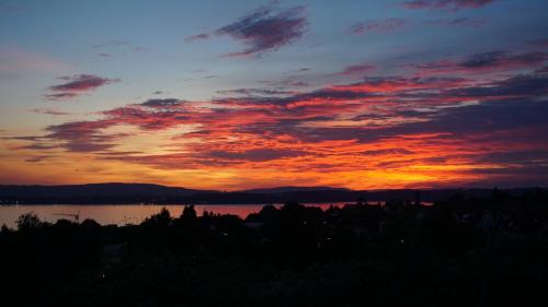 a sunset over a body of water with a red at Haus am Trielberg in Meersburg