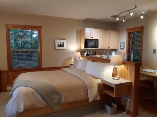 a bedroom with a large bed and a kitchen at Reef Point Oceanfront Bed and Breakfast in Ucluelet