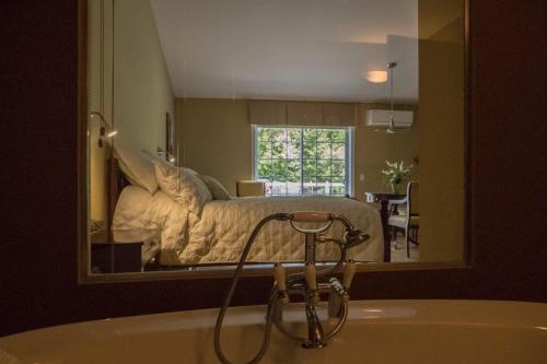 a bathroom mirror with a bed in a bedroom at Studio-hôtel Villegiature Saint-Sauveur in Piedmont