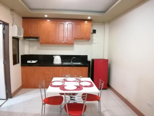 a kitchen with a white table and red chairs at Manora Apartment in Talisay