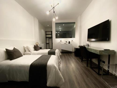 a bedroom with two beds and a desk and a television at Margot Fiera Verona in Verona
