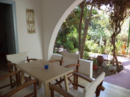 d'une salle à manger avec une table, des chaises et une fenêtre. dans l'établissement Lilo's Apartments, à Livadi Astypalaias