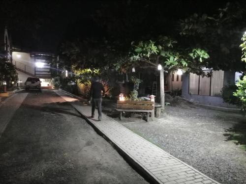 a man standing next to a park bench at night at Manora Apartment in Talisay