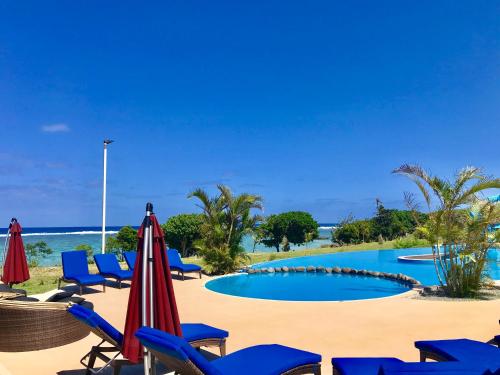 einen Pool am Strand mit Stühlen und Sonnenschirmen in der Unterkunft Yadua Bay Resort & Villas in Yandua