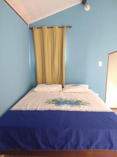 Cama en habitación con pared azul en Apartamento de Marconi, en Morro de São Paulo