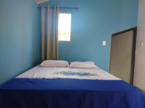 1 dormitorio azul con 1 cama con pared azul en Apartamento de Marconi, en Morro de São Paulo