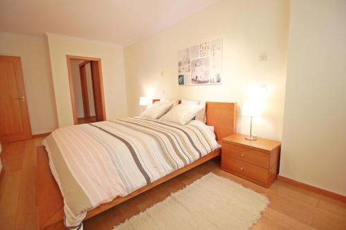 1 dormitorio con 1 cama y mesita de noche con lámpara en T2 Cascais Centro en Cascais