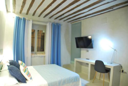 Schlafzimmer mit einem Bett, einem Schreibtisch und einem TV in der Unterkunft Apartamento NAO MALASAÑA - GRAN VIA in Madrid