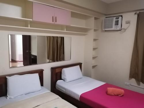 two beds in a small room with pink and white at Manora Apartment in Talisay