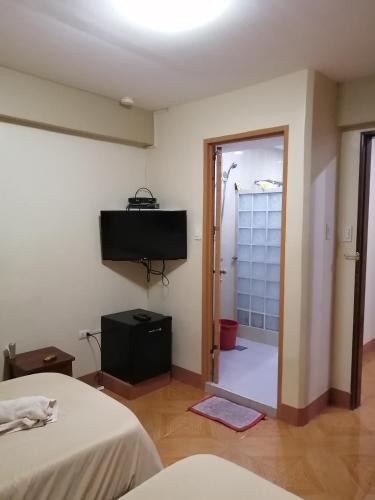 a room with two beds and a television on the wall at Manora Apartment in Talisay