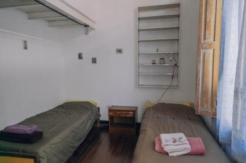 a bedroom with two beds and a table and a shelf at Experiencia Congreso in Buenos Aires