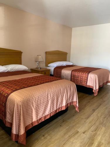Towne Inn في غلاسكو: سريرين في غرفة الفندق مع أرضيات خشبية