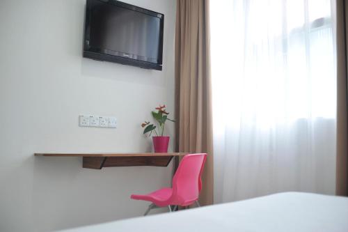 a room with a pink chair and a television at V Hotel Kuala Lumpur in Kuala Lumpur