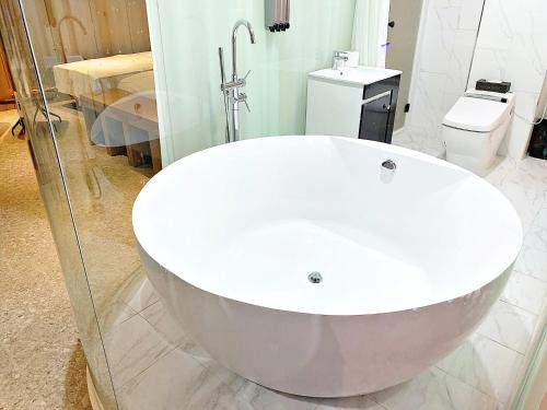 a white bath tub in a bathroom with a toilet at Biennale Hotel in Gwangju