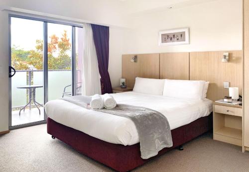 Habitación de hotel con cama grande y balcón. en Airport Ascot Motel en Brisbane