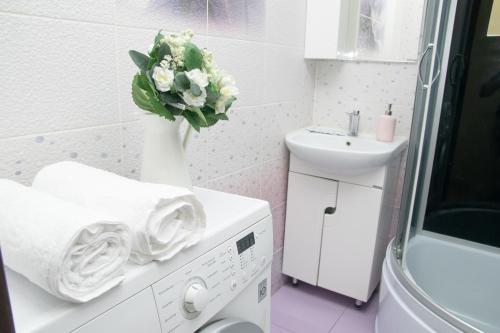 a white bathroom with a vase of flowers on a washing machine at 1-к квартира 9 января, 6 in Kemerovo