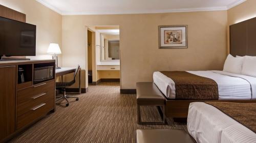 a hotel room with a bed and a desk with a television at Best Western Hollywood Plaza Inn Hotel - Hollywood Walk of Fame LA in Los Angeles