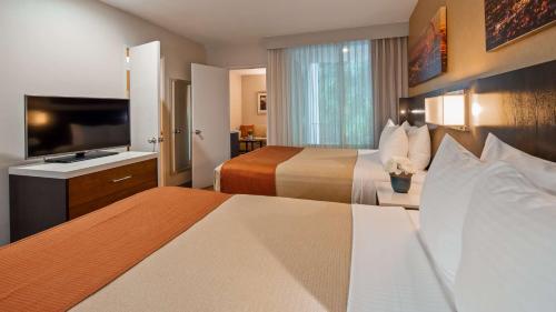 a hotel room with two beds and a flat screen tv at Best Western Royal Palace Inn & Suites in Los Angeles